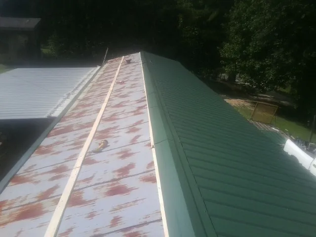 Old rusted panels beside newly installed green metal roofing — Wind Damage Roof Repair by Roofing Brothers in Pasadena